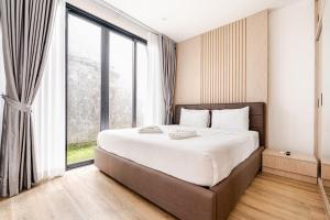 a bedroom with a large bed with a large window at 3BR Pool Villa JAAI in Ban Saiyuan (1) +30 photos