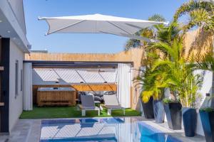 a patio with an umbrella and chairs and a pool at Villavender Boutique Suites in Netivot