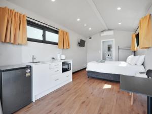 a bedroom with a bed and a kitchen with a sink at Parkes Cabins in Parkes