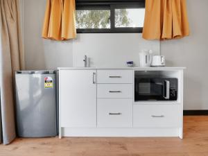a kitchen with a refrigerator and a microwave at Parkes Cabins in Parkes +4 photos