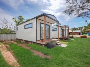 a tiny house sitting on top of a lush green yard at Parkes Cabins in Parkes