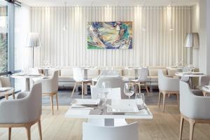 un restaurant avec des tables et des chaises blanches et une peinture murale dans l'établissement Mercure Hotel Golf Cap d'Agde, au Cap d'Agde