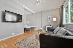 Forenom Serviced Apartments Oslo Rosenborg في أوسلو: غرفة معيشة مع أريكة وتلفزيون بشاشة مسطحة