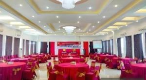 a banquet hall with red tables and chairs and a screen at Hotel 95 in Siantan