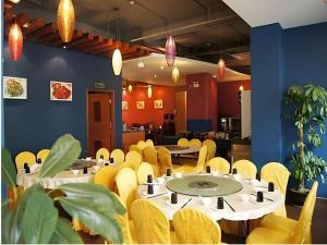 a dining room with tables and yellow chairs at Oriental Hotel in Dongguan