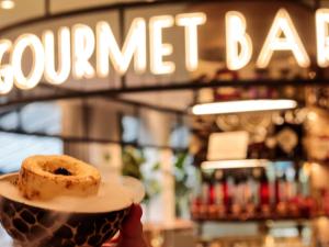 eine Person, die einen Teller mit einem Donut drauf hält in der Unterkunft Novotel Campo De Las Naciones in Madrid