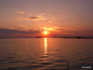 a sunset over a large body of water at Capitol Apartments in Grado +8 photos