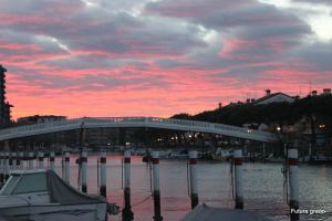 a bridge over a body of water with a sunset at Capitol Apartments in Grado