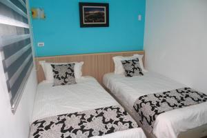 two beds in a room with blue walls at 500Km Home in Hualien City