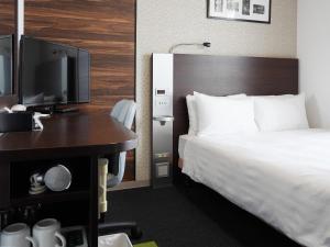 um quarto de hotel com uma cama, uma escrivaninha e uma TV em Comfort Hotel Tokyo Higashi Nihombashi em Tóquio