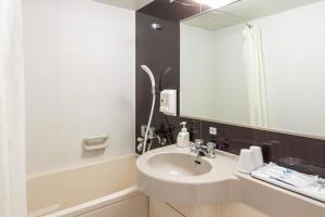 ein Badezimmer mit Waschbecken und Spiegel in der Unterkunft Comfort Hotel Tomakomai in Tomakomai + 23 Fotos