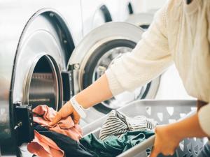 a woman putting clothes in a washing machine at Comfort Hotel Kitami in Kitami