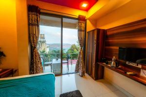 a living room with a large window with a view at Strawberry County in Panchgani