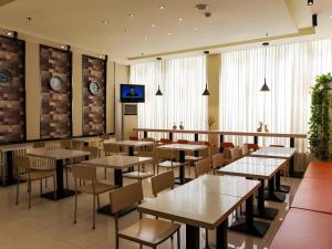 淄博Jinjiang Inn Zibo People's Park Liuquan Road的有桌椅和电视的餐厅