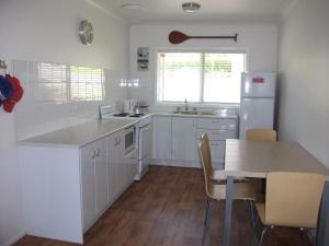 een keuken met witte kasten, een tafel en een koelkast bij Tomaree Lodge in Nelson Bay