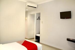 ein Schlafzimmer mit einem Bett und einem Fernseher an der Wand in der Unterkunft Collection O Manggis Inn in Jakarta