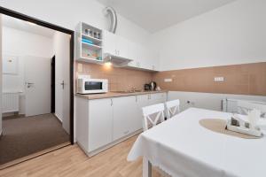 eine Küche mit weißen Schränken, einem Tisch und einer Mikrowelle in der Unterkunft Apartmán U Dubu in Jablonné nad Orlicí