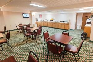 a dining room with tables and chairs and a kitchen at Baymont by Wyndham Lake George in Lake George
