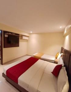 ムンバイにあるHotel AI inの大きなベッドとテレビのある寝室