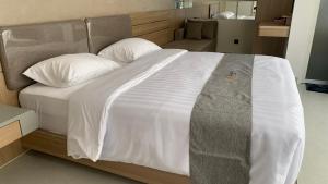 uma cama com lençóis e travesseiros brancos em um quarto em di Turgo Village em Balong mais 4 fotografias