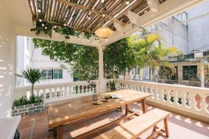an outdoor patio with a wooden table and benches at Glass Apartment With Big Balcony in Hanoi