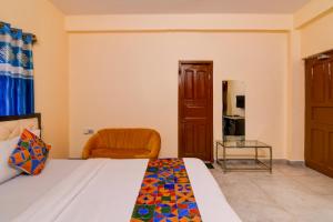 a bedroom with a bed and an orange chair at FabHotel Samanta in kolkata