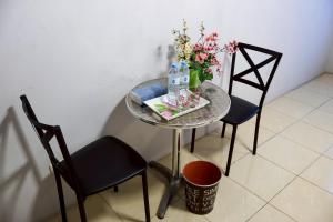 a table with a vase of flowers and two chairs at DD House Apartment in Bangkok