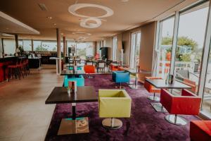 ein Restaurant mit Tischen und Stühlen und Fenstern in der Unterkunft Starling Hotel Lausanne in Lausanne