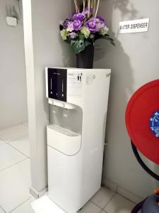 un frigorifero bianco con un vaso di fiori sopra di Pendang Suite Hotel PLT a Pendang