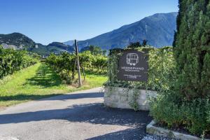 a sign in a vineyard with a mountain in the background at Verdepiano Bed & Camping in Riva del Garda