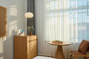 Una habitación con una silla y una mesa y una ventana. en Floral Hotel Banlan China Korean Folk Park, 