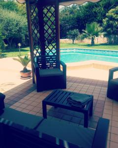 - une terrasse couverte avec 2 chaises et un banc à côté de la piscine dans l'établissement VanessaHolidayHome, à Cava dʼAliga
