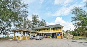ein gelbes Gebäude mit zwei davor geparkt in der Unterkunft OYO 90315 Chalet Pantai Rantau Panjang in Kampong Kandang
