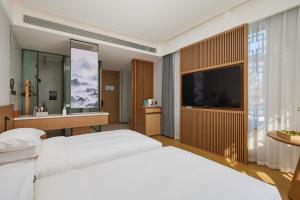 Un dormitorio con una cama grande y un televisor. en Floral Hotel Banlan China Korean Folk Park,  26 fotos más