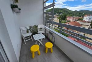 a balcony with two yellow chairs and a table at Apartman 44, sa garažom, Mejdan Banja Luka in Banja Luka