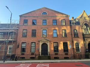 an old brick building with a black door on a street at Studio Seven - Leeds City Centre in Central Station