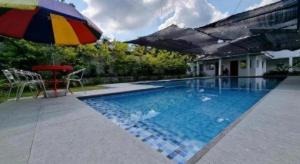 una piscina con un ombrellone colorato e un tavolo di CMJ Private Resort a Banaba Cerca