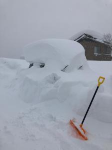 a car covered in snow with an orange shovel in it at Edo-Ko House in Myoko
