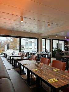 un ristorante con tavoli e sedie in legno e finestre di Seehotel Forst a Forst