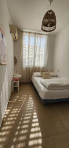 a bedroom with two twin beds and a window at Modern Family Apartment by IsrApart in H̱olon