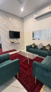 ein Wohnzimmer mit grünen Sofas und einem roten Teppich in der Unterkunft شاليه ڤيو in Ras al-Hadd