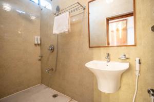 ein Badezimmer mit Waschbecken und Dusche mit Spiegel in der Unterkunft Koramangala SeasonsSuites in Bangalore