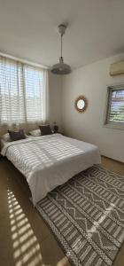 a bedroom with a large white bed with a rug at Modern Family Apartment by IsrApart in H̱olon