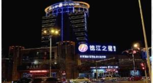 a tall building with blue lights on it at night at Jinjiang Inn Select Zhenjiang Yangzhong Yangzi Middle Road in Yangzhong