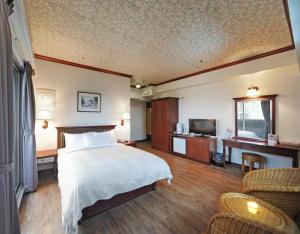 um quarto de hotel com uma cama e uma televisão em Kenting Holiday Hotel em Hengchun South Gate