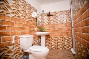 Wilpattu Wild Cottages في Nochchiyagama: حمام به مرحاض وجدار من الطوب
