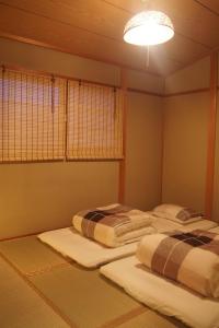 two twin beds in a room with a light at Love Kyoto Kyoenkan in Kyoto
