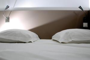 a bed with two pillows and a light above it at Résidence Thalacap in Cap d'Agde
