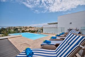 una fila de tumbonas en el techo de una piscina en Villa Gaia - Sunset Views, Indoor Heated Pool, Sauna and Games Room, en Mellieħa