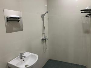 a white bathroom with a sink and a mirror at Passifika Hotel Maluk in Maluk